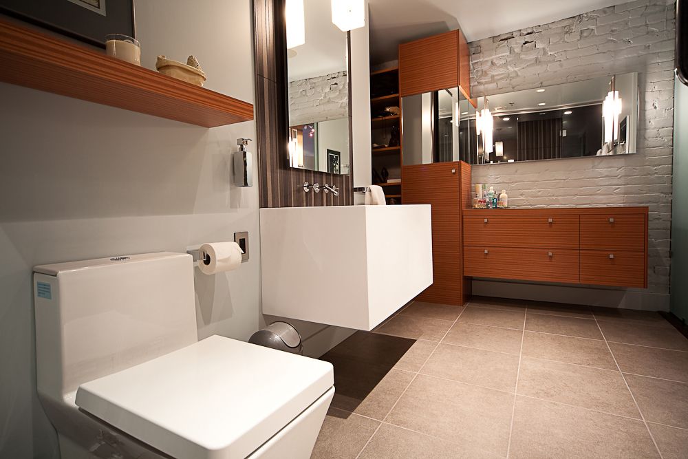 modern bathroom reno with floating sink, built-in cabinets and exposed brick wall