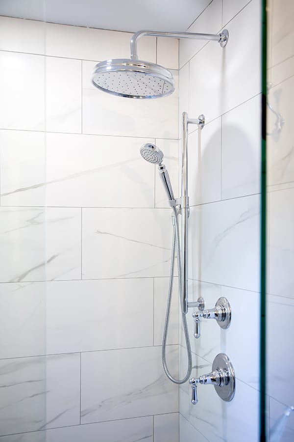 custom shower with tiled walls, chrome fixtures and glass doors